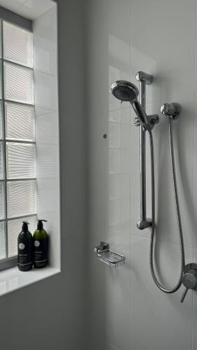 a shower in a bathroom with two bottles on a shelf at Carlton 1910 Manly Hideaway in Sydney
