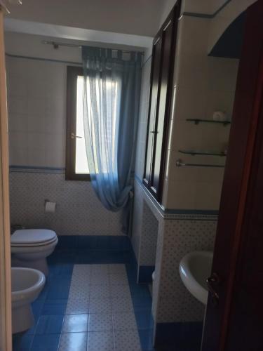 a bathroom with a toilet and a sink and a window at Villa Orchidea in Praia a Mare