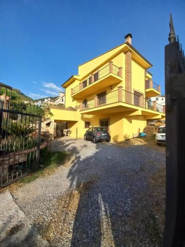 a yellow house with a car parked in the driveway at Villa Orchidea in Praia a Mare