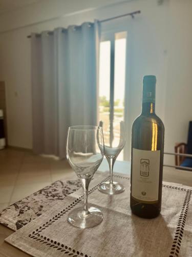 a bottle of wine and two wine glasses on a table at Niko's apartments 1 in Elafonisos