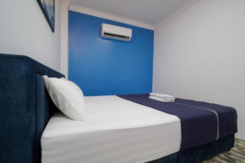 a bed in a room with a blue wall at BOSS Hotel in Ipoh