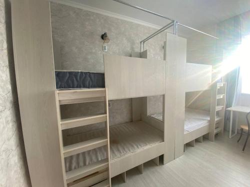 a white bunk bed in a room with a table at Friendly in Astana