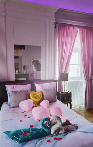 un lit avec deux animaux en peluche et des ballons dessus dans l'établissement Suite Romantique La Charmante, à Villersexel
