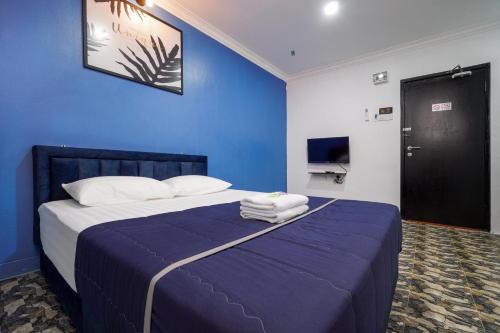 a blue bedroom with a bed with towels on it at BOSS Hotel in Ipoh