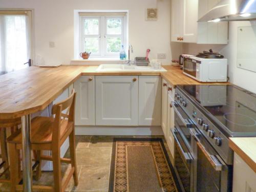 a kitchen with white cabinets and a wooden counter top at Bridge Cottage in Mitchel Troy