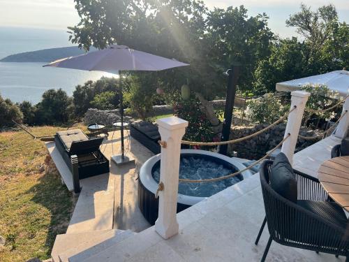 a hot tub with an umbrella on a patio at Deja Blue Ustrine in Ustrine