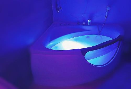 La salle de bains est pourvue d'une baignoire bleue dans une chambre sombre. dans l'établissement Suite Romantique La Charmante, à Villersexel