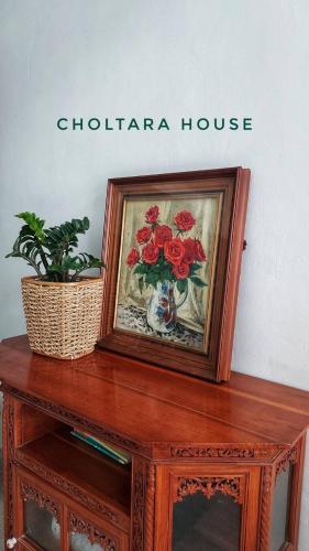 a picture of a vase of flowers on a wooden table at Choltara house in Hat Yai