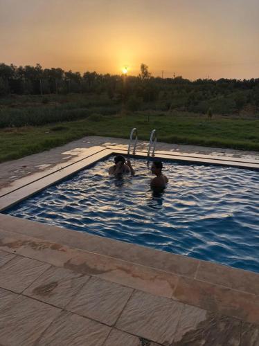 two people in a swimming pool at sunset at Villa avec piscine in Meknès