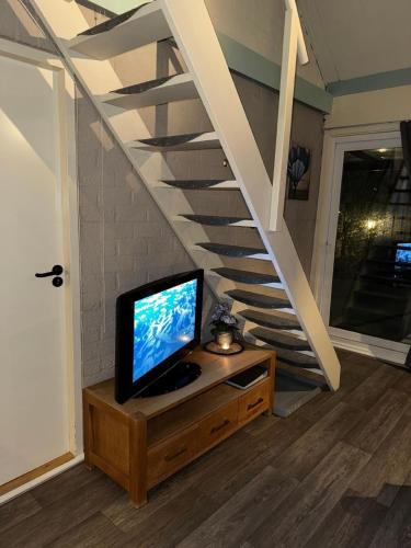 a tv sitting on a dresser next to a staircase at Ferienhaus in Stavenisse mit Garten, Whirlpool und gemeinsamem Pool in Stavenisse