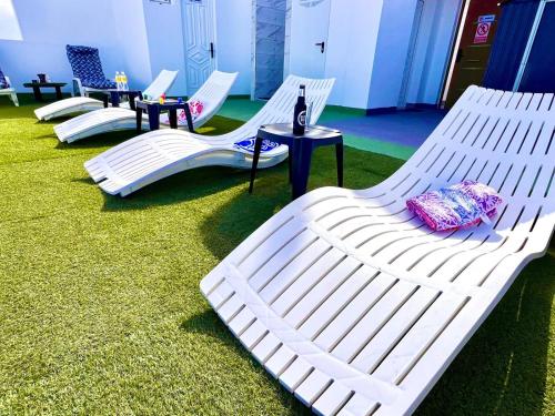 a group of white chaise lounges on the grass at Animoss! Apartments - 10 modern apartments near city center & beach in Santa Maria
