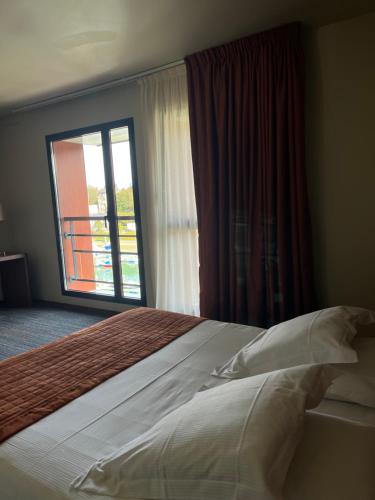 a bed in a hotel room with a large window at Hotel du Casino in Saint-Valéry-en-Caux