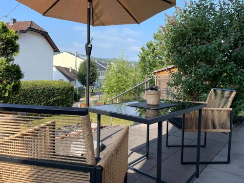 ein Tisch und Stühle mit einem Sonnenschirm auf einer Terrasse in der Unterkunft Ferienwohnung in Adenau am Nürburgring in Adenau