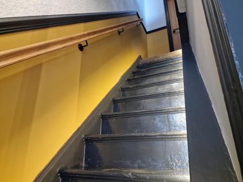 a stairway leading up to a yellow wall at Torquay Villas - Stylish getaway in Hull