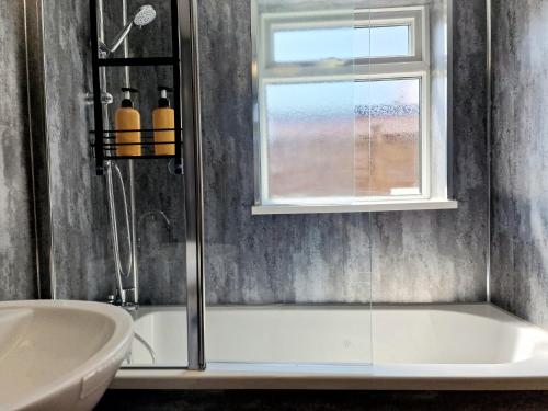 a bathroom with a shower and a tub and a window at Torquay Villas - Stylish getaway in Hull