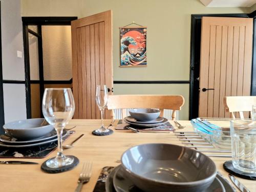 a wooden table with glasses and plates on it at Super Stylish and Vibrant 3 Bed Getaway in Hull
