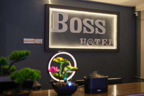 a sign on a wall above a table with plants at BOSS Hotel in Ipoh