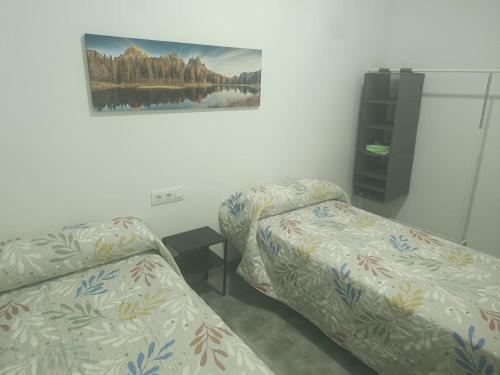 una stanza con due letti e un quadro sul muro di Apartamentos Turísticos Atalaya a Minas de Ríotinto