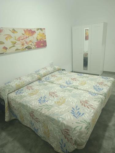 a bed in a white room with a floral bedspread at Apartamentos Turísticos Atalaya in Minas de Ríotinto