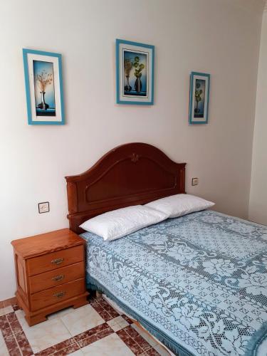 a bedroom with a bed and a dresser and pictures on the wall at Dar Al-Amira - Fnideq Beach Apartment in Fnidek