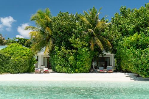a resort on a beach with chairs and trees at Dhigali Maldives - A Premium All-Inclusive Resort in Raa Atoll