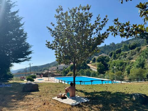 a man sitting on a blanket next to a swimming pool at Raízes da Serra - Casa Alvoco in Alvoco da Serra