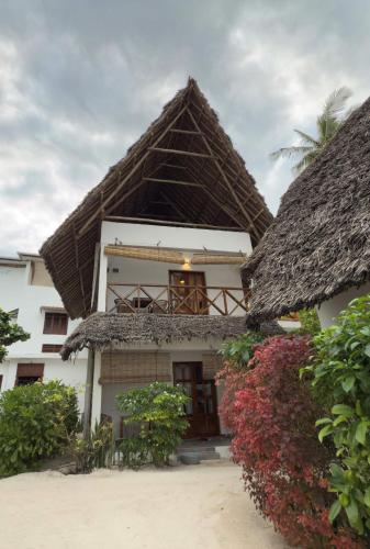 a building with a thatched roof and a balcony at Savera Beach Houses in Jambiani