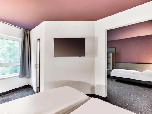 a bedroom with two beds and a flat screen tv at B&B Hotel Bremen-Altstadt in Bremen