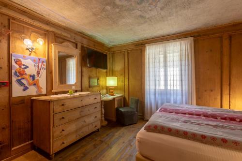 a bedroom with a bed and a dresser at Historic Hotel Ristorante La Stua in Cavalese