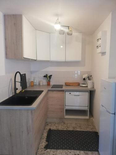 une cuisine avec des armoires blanches et un évier dans l'établissement Appartement à Nîmes, au coeur d'un terrain de 3600m2 avec piscine, à Nîmes