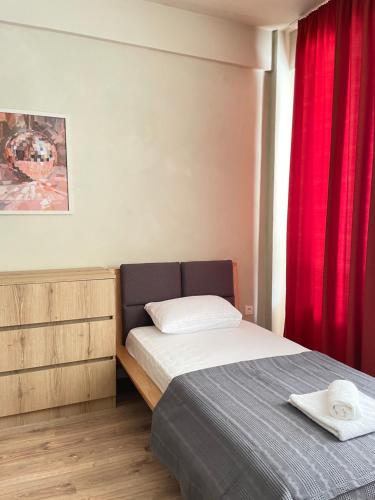 a bedroom with a bed and a red curtain at Lomi's Homey in Tbilisi City