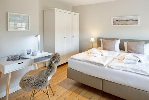 una camera da letto con un letto con una scrivania e una sedia di Dünenzauber a List