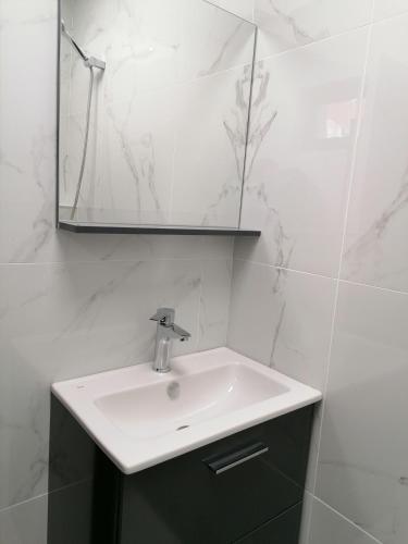 a white bathroom with a sink and a mirror at гест хаус паркова 33 in Razgrad