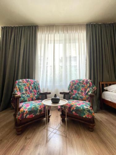 a room with two chairs and a table and a bed at Lomi's Homey in Tbilisi City