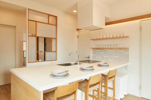 a kitchen with a large white island with chairs at Tokyo Sky Suite Hotel in Tokyo
