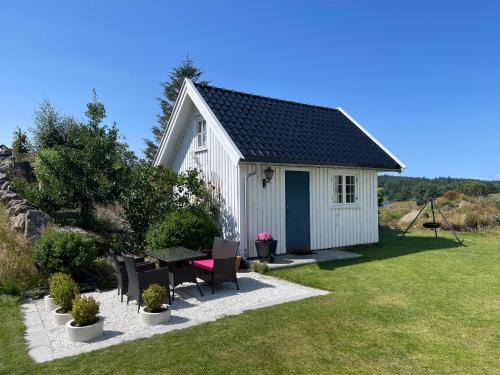 a white shed with a table and chairs in a yard at Villa Krågenes in Farsund