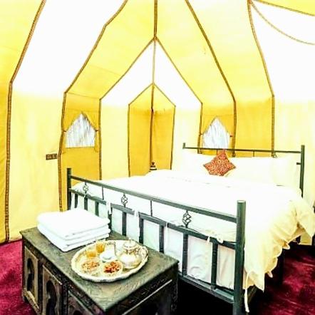 メルズーガにあるTenere luxury campのベッドルーム1室(ベッド1台、テーブル、食器付)