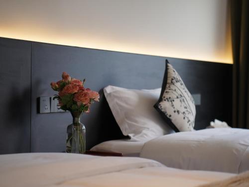 a vase of flowers on a table next to two beds at Huangshan Hongcun Weizhashan Xunxi Hotel in Huangshan