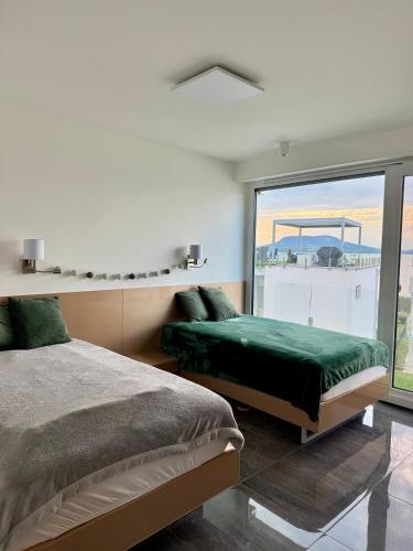 a bedroom with two beds and a large window at Villapark apartman A-B 12 in Fonyód