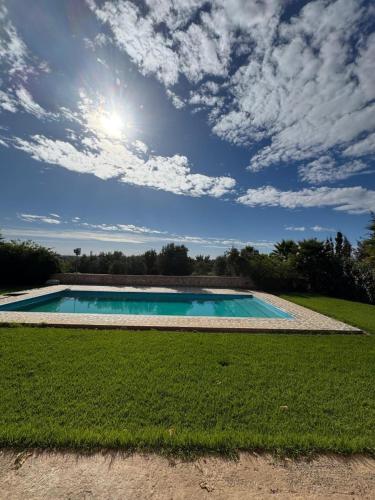 a swimming pool in a field with a cloudy sky at Villa zaytoun in Agadir