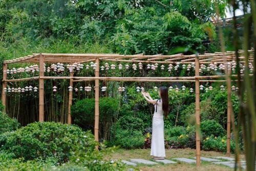 a woman standing in front of a wooden arch with flowers at Lynn Times Thanh Thuỷ hotspring-KS 35 tầng- My Home in Phú Thọ