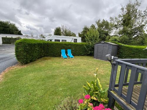 two blue chairs sitting in the grass in a yard at Omaha beach mobilhome in Colleville-sur-Mer
