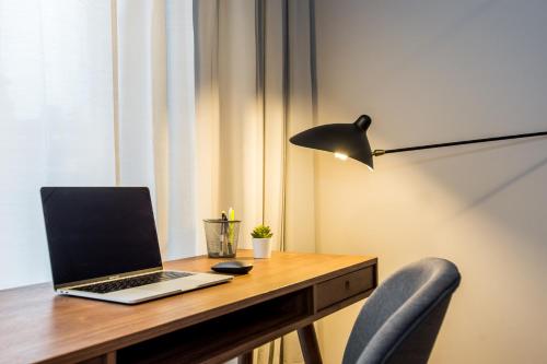 un ordenador portátil sentado en un escritorio de madera con una lámpara en Super-Apartamenty Presidential Suite, en Poznan
