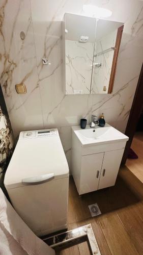 a white bathroom with a sink and a mirror at Black Flox AparTment in Drama