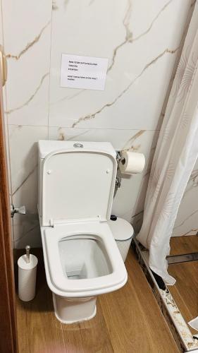 a white toilet in a bathroom with a sign above it at Black Flox AparTment in Drama