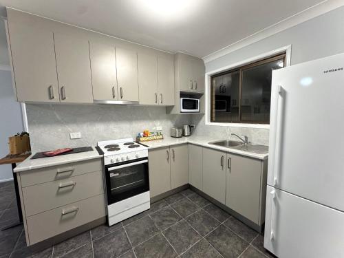 a kitchen with white cabinets and a white refrigerator at Nestled on Smith in Stanthorpe
