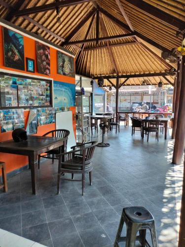 a restaurant with tables and chairs and a cat sitting on a table at Dhita Bila Bungalows & Dive in Amed