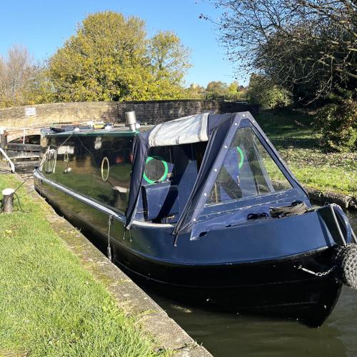 a blue boat parked in the water next to aicked at Daisy Mutler Holiday Boat Hire in Bletchley