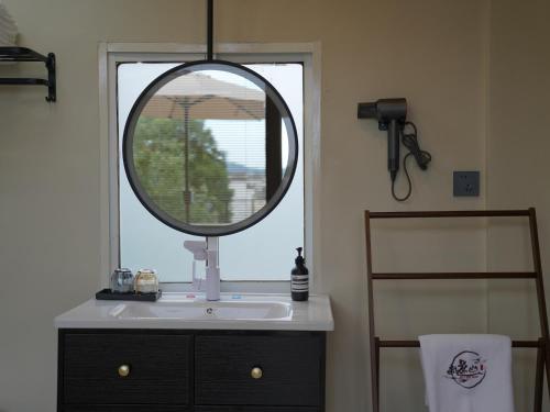 a bathroom with a mirror over a sink and a window at Huangshan Hongcun Weizhashan Xunxi Hotel in Huangshan