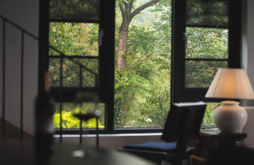 a room with a window with a table and a lamp at Lijiang Jijian Xiangwang SOOOAN Luxury Resort Hotel in Lijiang